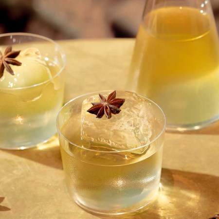 Two glasses and a decanter of a clarified milk punch made with Equiano Rum