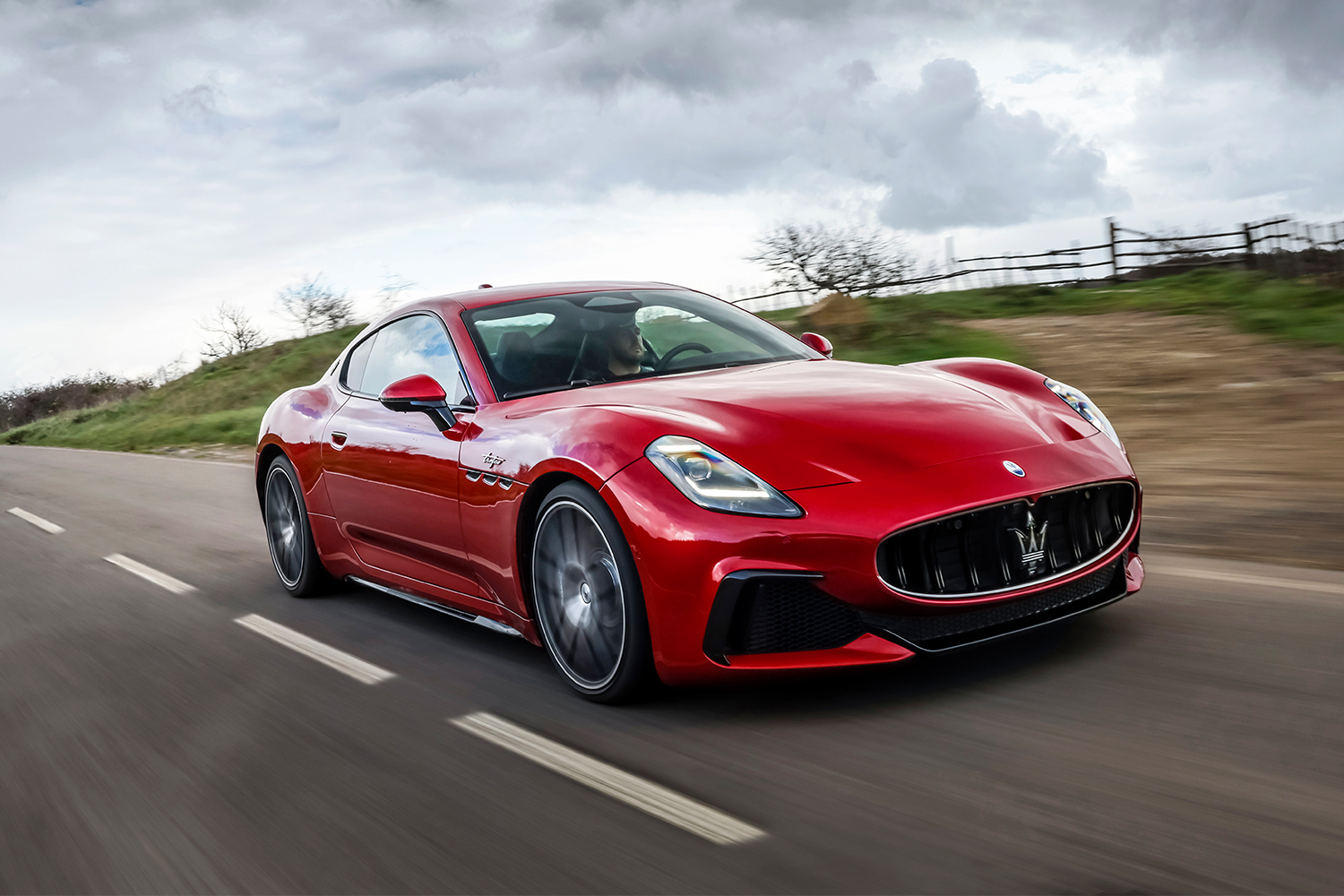 The red 2024 Maserati GranTurismo Trofeo driving down a country road