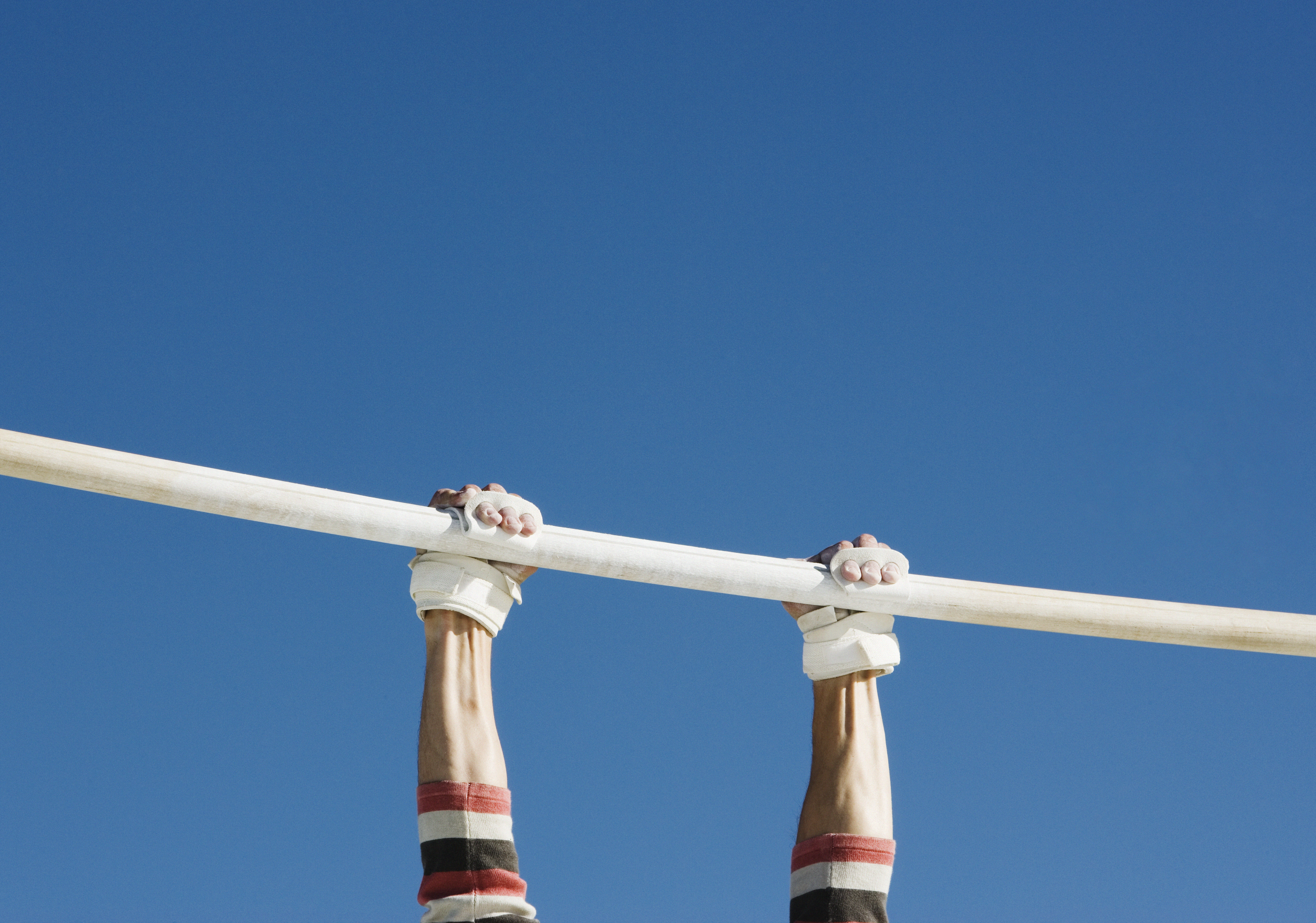 A pair of hands clutching a gymnastics beam. Grip strength may be related to living longer, according to some studies.