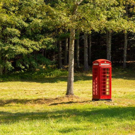 A red telephone booth in a meadow.