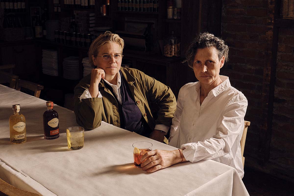 Via Carota's Jody Williams and Rita Sodi at a dining table with their line of bottled cocktails