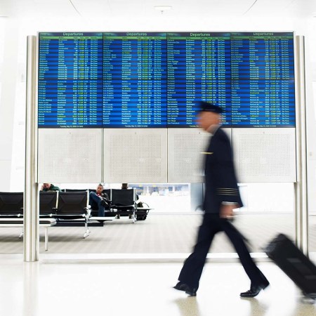 a pilot rolling his bag through the airport