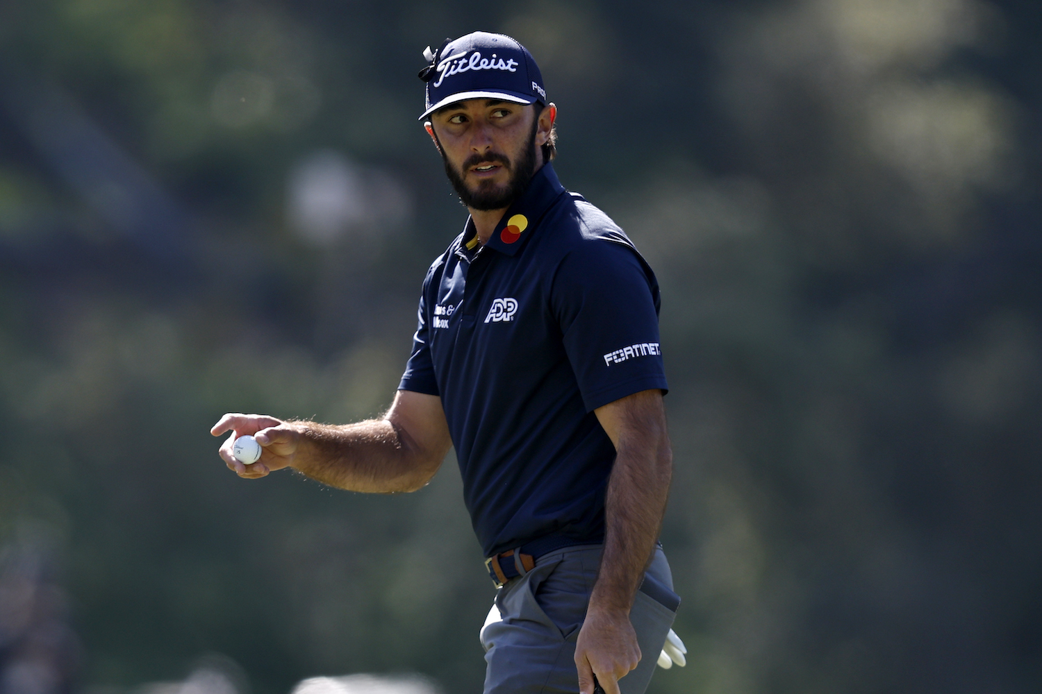 Max Homa walks a course holding his golf ball