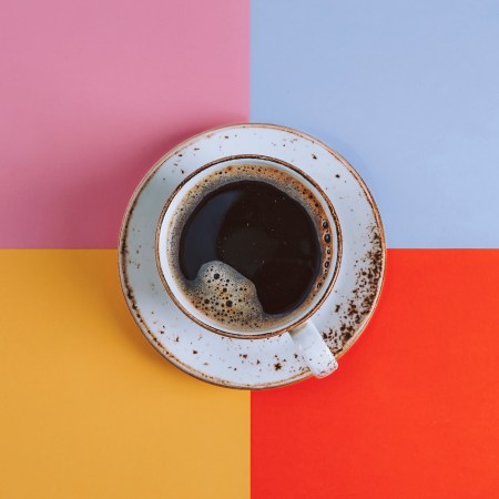 A cup of coffee against a multi-colored background.