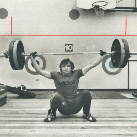 A vintage photo of a lifter struggling to lift a bar.