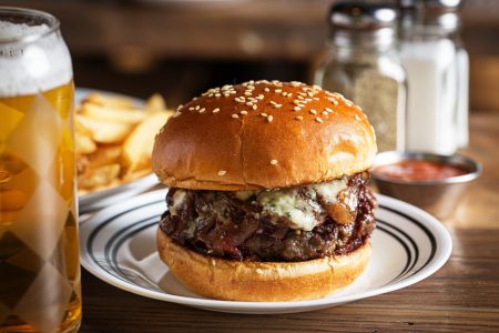 A burger next to a drink and fries