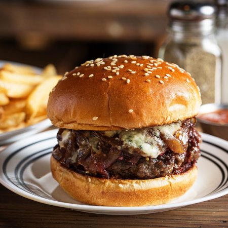 A burger next to a drink and fries