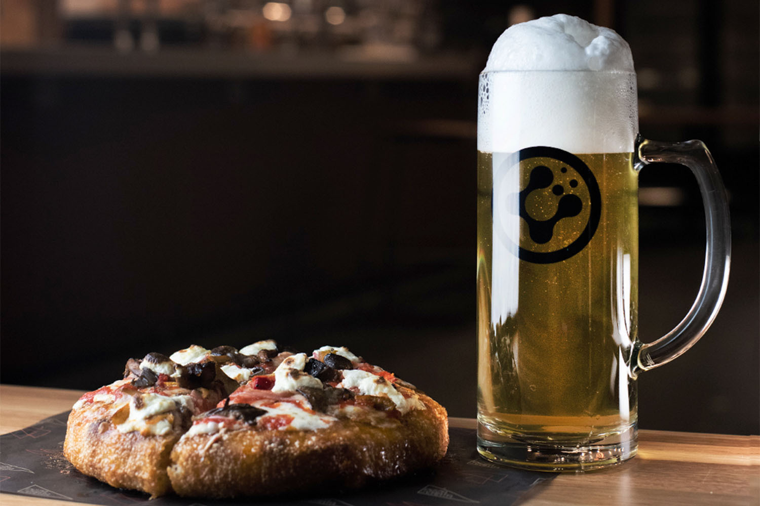 A whole pizza and beer mug.