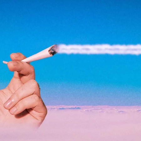 A hand holding a joint above the clouds while the smoke trails across the sky. Here's our guide to getting stoned while flying on a plane.