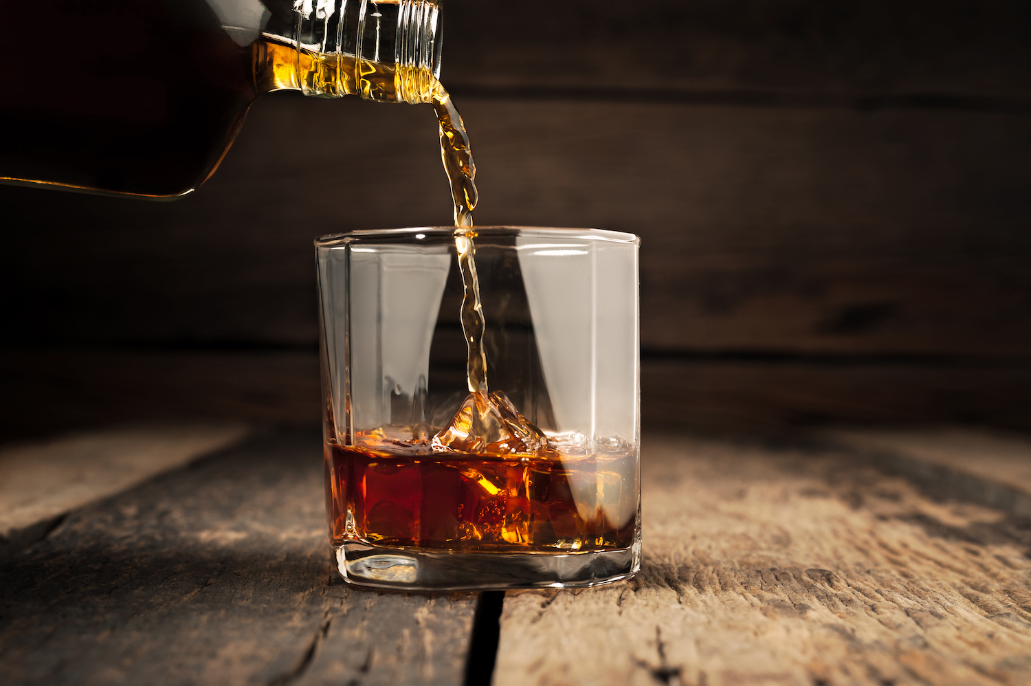 close-up of pouring dark rum on the rocks