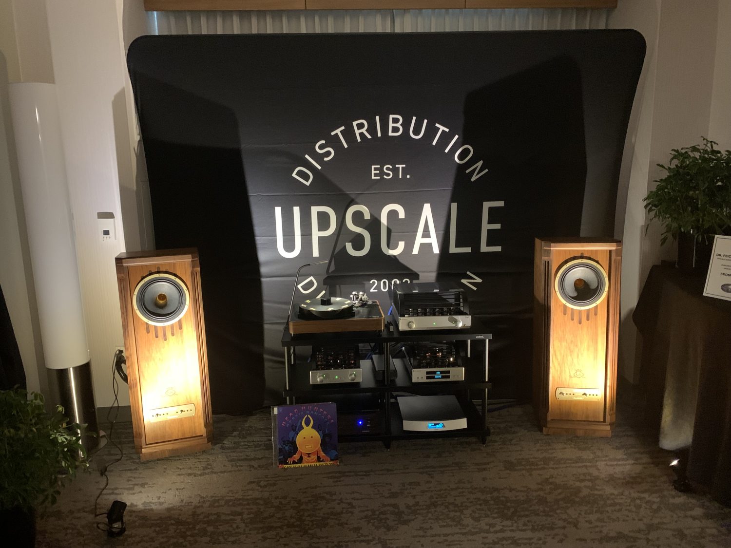 A Dr. Feichert Trio SE turntable and two brown Tannoy Kensington speakers in a dark room with spotlights.