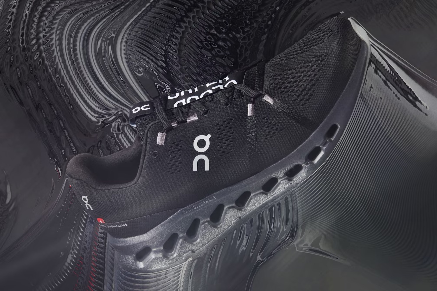 a pair of black On running sneakers on a black background