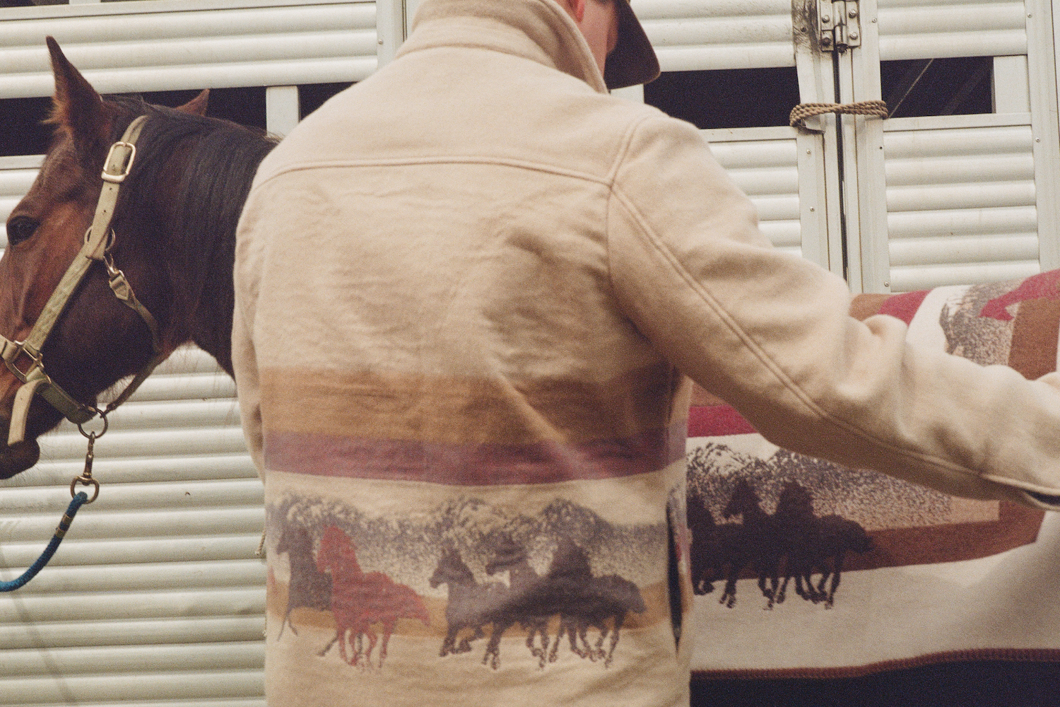 a model wearing a OOTD x Woolrich jacket hanging around a horse