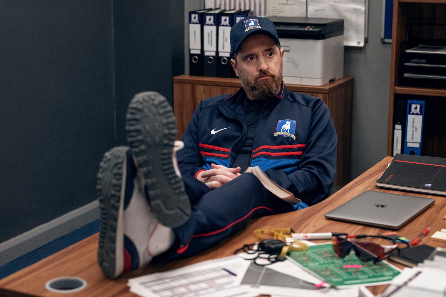 Coach Beard from Ted Lasso at his desk.