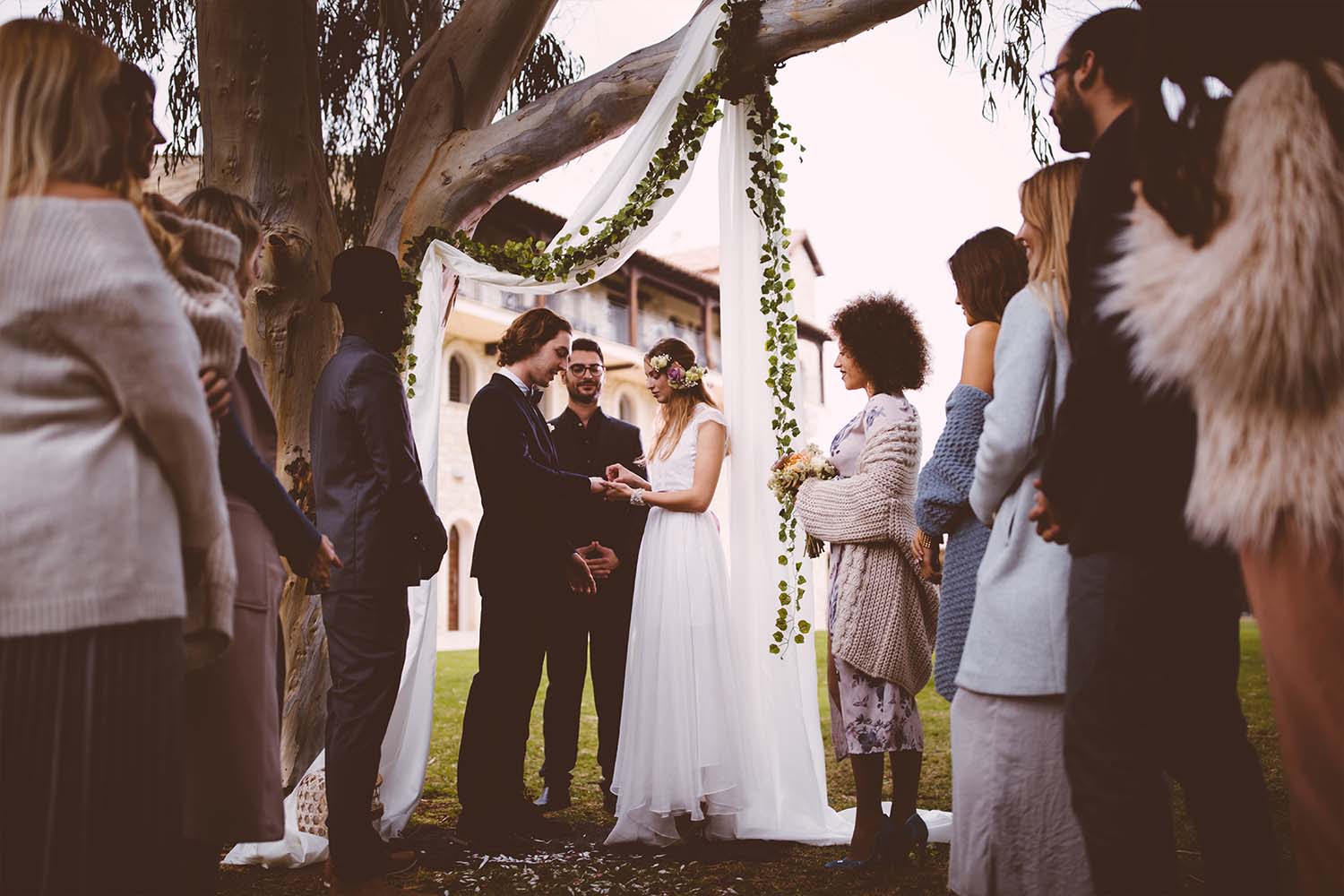 Couple exchanging vows in front of guests. Here's how much it'll cost to be a wedding guest this year.