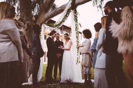Couple exchanging vows in front of guests. Here's how much it'll cost to be a wedding guest this year.