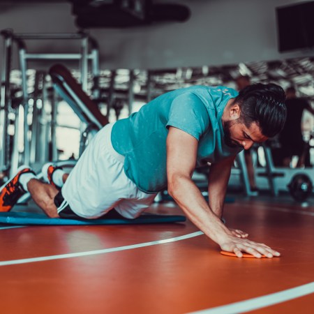 A man doing push-ups with his knees on the floor.