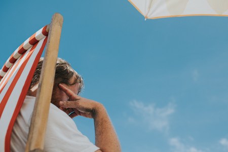 A man staring at the sky, sitting in a beach chair.