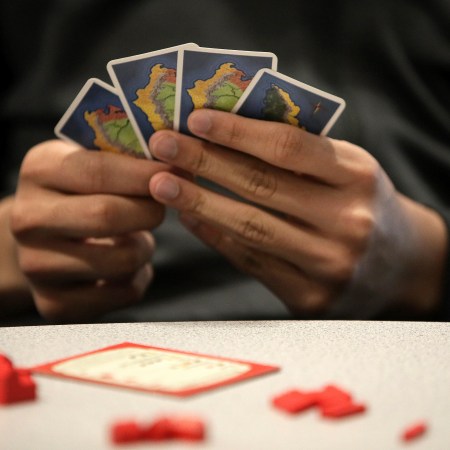 A man holding Catan playing cards in his hands. Here's why you should play Klaus Teuber's game for your health.