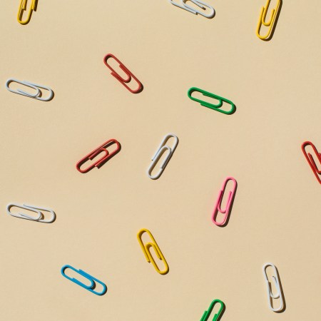 A bunch of paper clips scattered around a beige background. Here's how the habit-forming Paper Clip Strategy works.