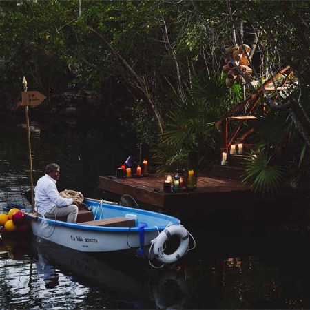 A man in a boat in front of La Isla Secreta, a speakeasy you can only reach by boat in Riviera Maya