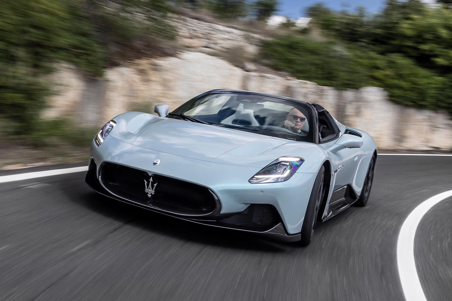A Maserati MC20 Cielo in blue driving around a corner