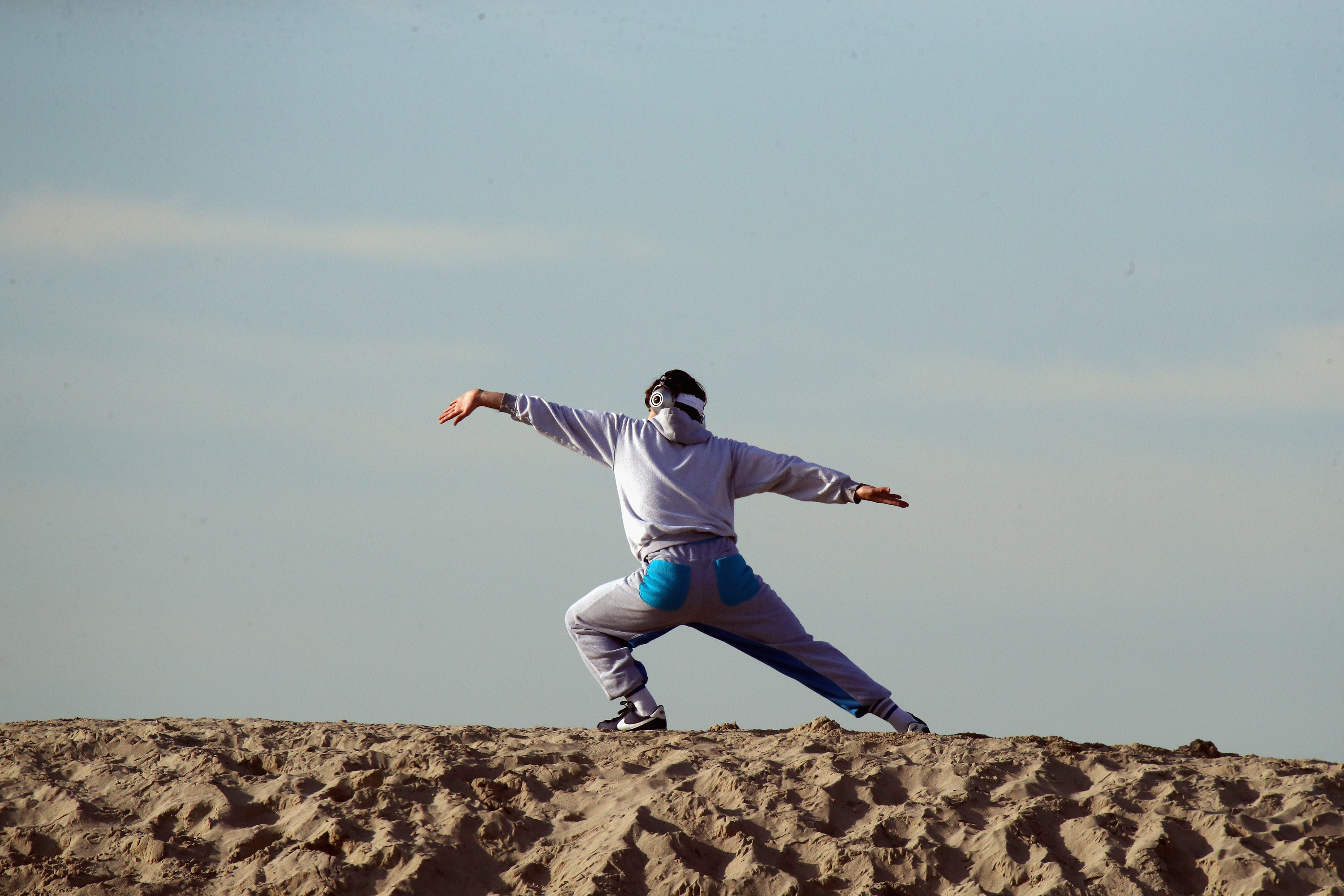 A man doing a morning workout on the sand with the sky behind him.