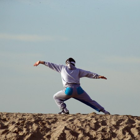 A man doing a morning workout on the sand with the sky behind him.