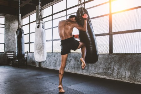 A Muay Thai fighter strikes a heavy bag with his knee.