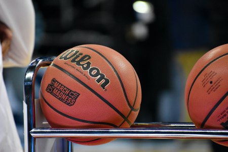 A Wilson brand basketball with "March Madness" scrawled on it, sits in an aluminum ball rack