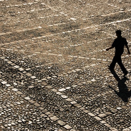 A man walking across cobblestones.