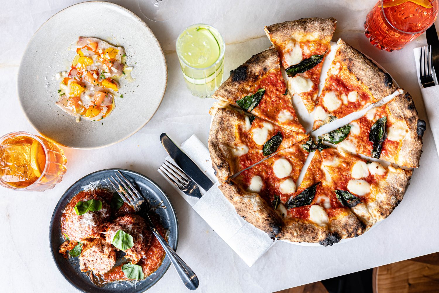 pizza and meatballs on a plate with a cocktail.
