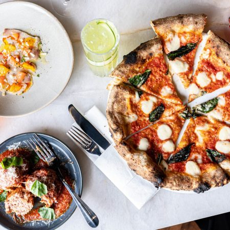 pizza and meatballs on a plate with a cocktail.