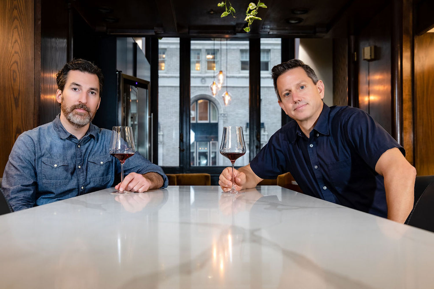 Sommeliers Kelly Evans and Michael Lagau of Bin 415 posing at a table with glasses of wine in their hands