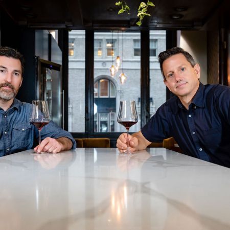 Sommeliers Kelly Evans and Michael Lagau of Bin 415 posing at a table with glasses of wine in their hands