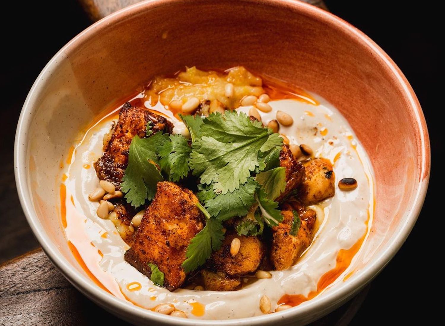 fish, pine nuts and spices in a bowl covered in a dressing.