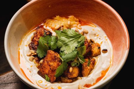 fish, pine nuts and spices in a bowl covered in a dressing.