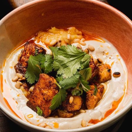 fish, pine nuts and spices in a bowl covered in a dressing.