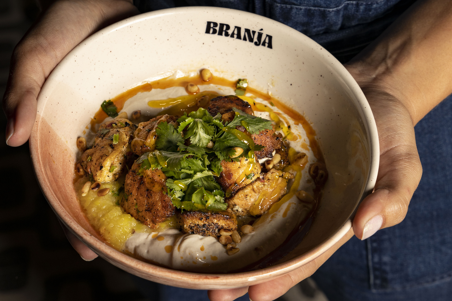 fish, pine nuts and spices in a bowl covered in a dressing.