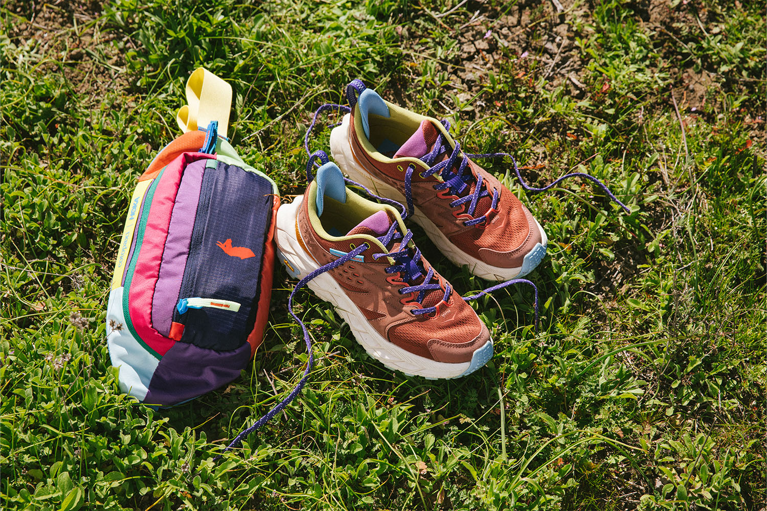 a pair of HOKA x Cotopaxi Anacapa Breeze Low Hiking Shoes on a grass background
