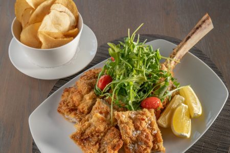 Plated veal, salad and potato chips.