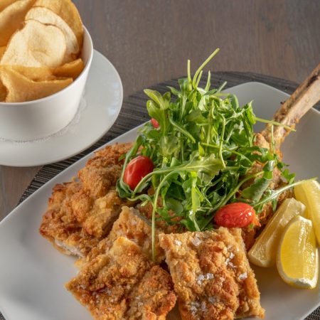 Plated veal, salad and potato chips.