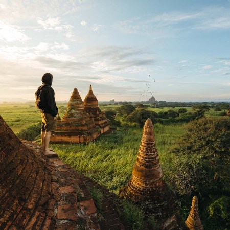 tourist standing on beautiful pagoda during a stunning sunrise in Bagan, Myanmar