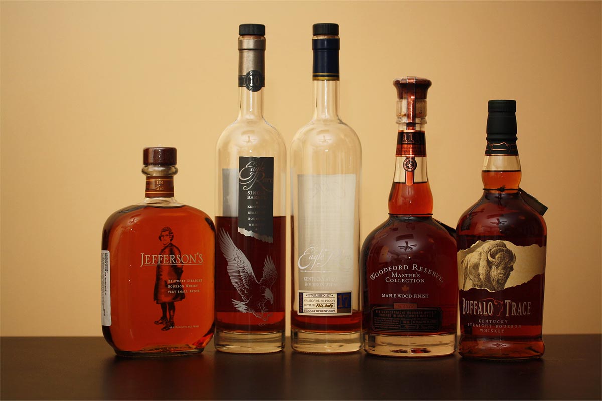 Five bottles of elevated bourbon on a table.
