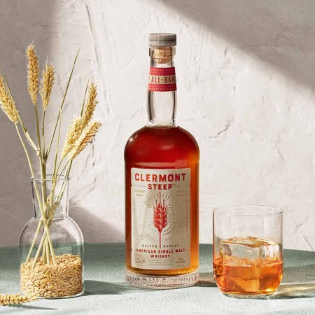A bottle of Clermont Steep and a glass of ice and whiskey. Clermont is a new American Single Malt from the producers of Jim Beam.
