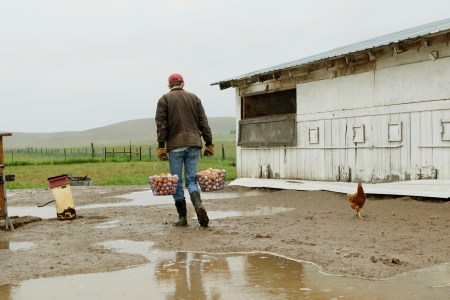 A farmer walking with two baskets of chicken eggs. This exercise move, called the farmer's carry, can be replicated in real life or the gym.