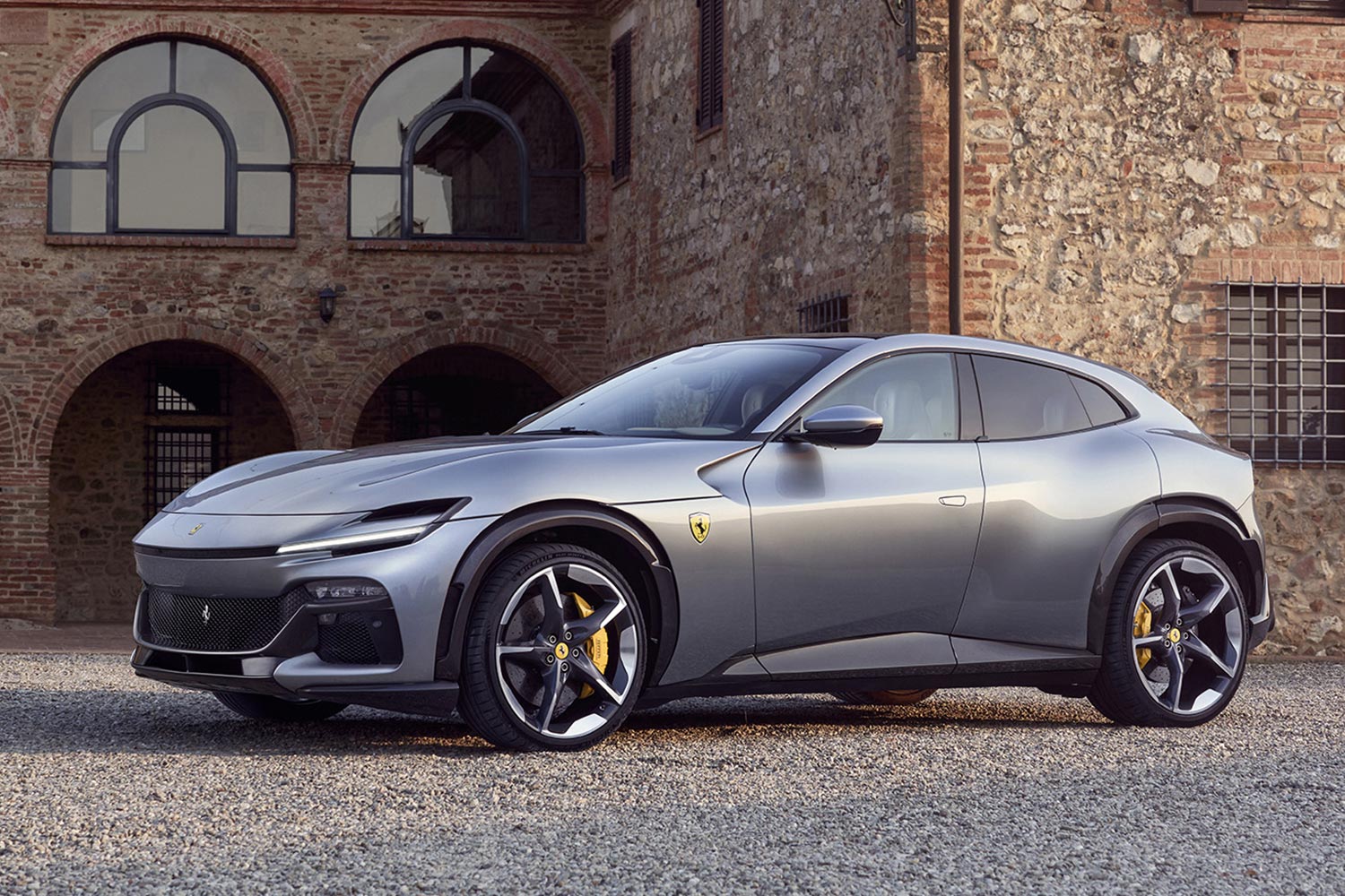 The Ferrari Purosangue SUV in silver sitting next to an old Italian villa