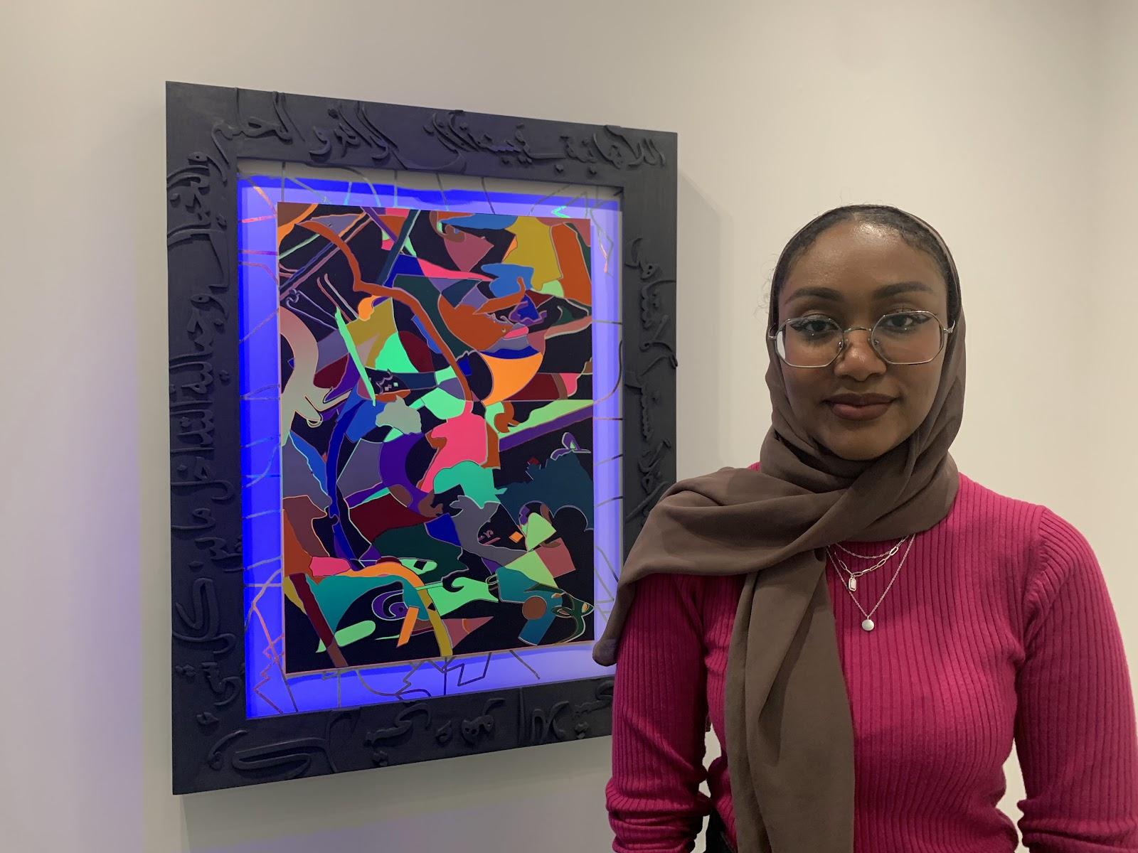 graduate student posing next to art work