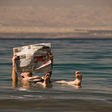 a man floating in the water reading a newspaper