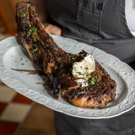 A waiter holding an ax handle steak at St. Anselm, one of the best steakhouses in Washington, D.C.